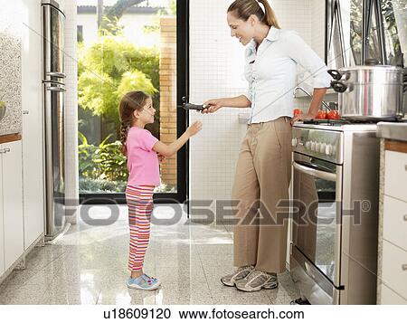 Mother giving telephone to daughter in kitchen View Large Photo Image Stock Image - Mother giving telephone to daughter in kitchen. Fotosearch