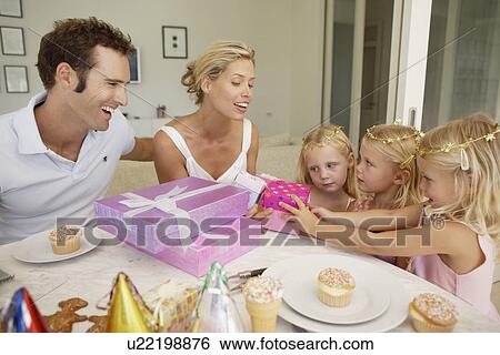 Stock Photograph - Parents giving birthday presents to triplets. Fotosearch