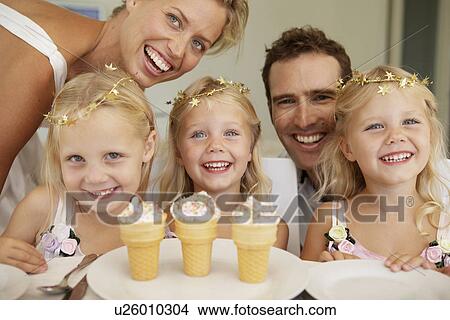 Triplets having ice cream, parents in background View Large Photo Image Picture - Triplets having ice cream, parents in background. Fotosearch
