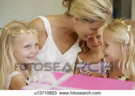 Stock Image - Triplets with mother, birthday present in foreground. Fotosearch