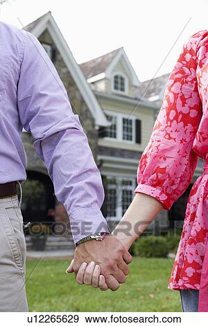 Mature couple holding hands near house View Large Photo Image Stock Photo - Mature couple holding hands near house. Fotosearch