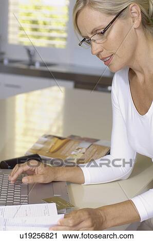 Stock Image - Mature woman booking travel via internet. Fotosearch