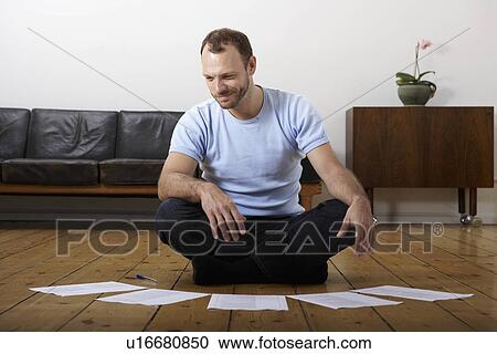 Mid adult man doing paperwork on floor View Large Photo Image Stock Image - Mid adult man doing paperwork on floor. Fotosearch
