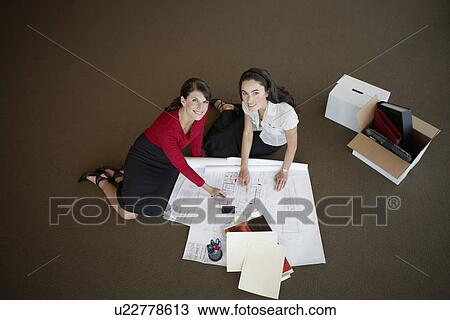 Two businesswomen examining blueprints on floor (portrait, high angle view) View Large Photo Image Stock Image - Two businesswomen examining blueprints on floor (portrait, high angle view). Fotosearch