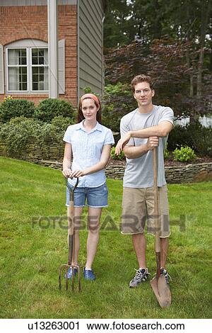Stock Image - Young couple with garden fork and spade. Fotosearch