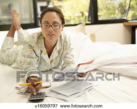 Young woman counting bills on bed View Large Photo Image Stock Photo - Young woman counting bills on bed. Fotosearch