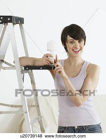 Stock Photo - Young Woman Holding Long-Life Light bulb. Fotosearch