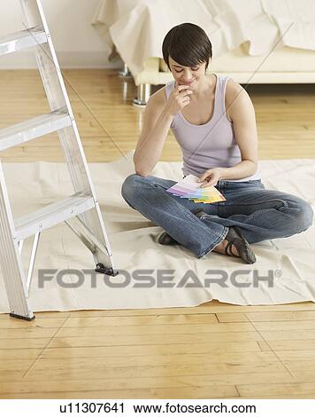 Stock Image - Young Woman Looking at Color Swatches on Floor. Fotosearch