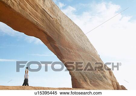 Man standing on head under arched rock View Large Photo Image Stock Photography - Man standing on head under arched rock. Fotosearch