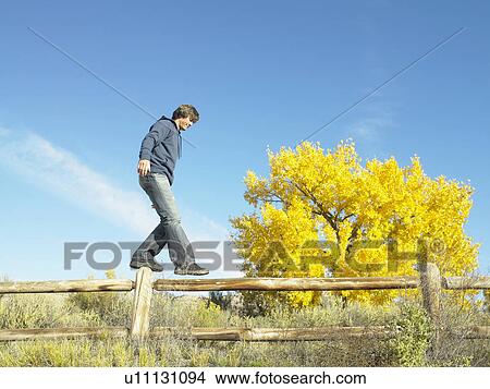 Picture - Man walking on wooden fence, low angle view. Fotosearch