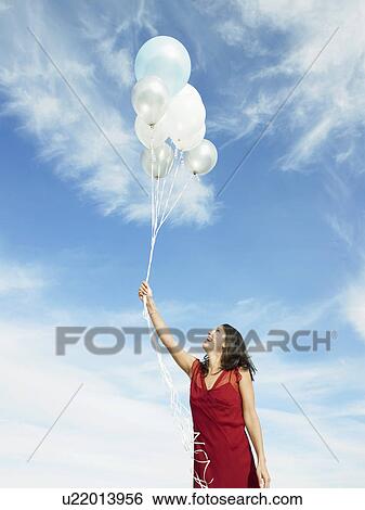 Stock Photograph - Mid adult woman holding balloons. Fotosearch
