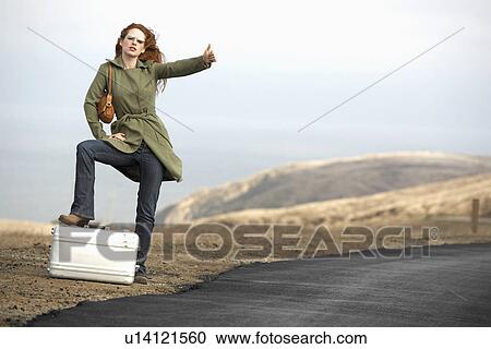 Stock Image - Woman hitchhiking with metal briefcase. Fotosearch