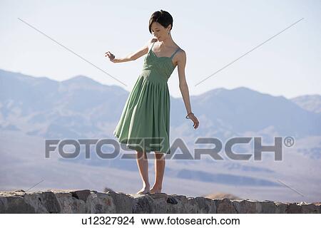 Woman in dress walking on stone wall View Large Photo Image Picture - Woman in dress walking on stone wall. Fotosearch