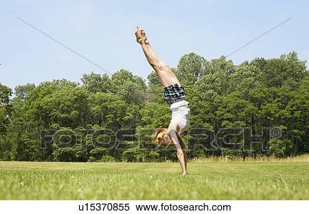 Stock Photography - Woman standing on hands in field. Fotosearch
