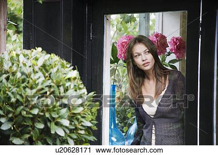 Woman looking through window near flowers View Large Photo Image Stock Image - Woman looking through window near flowers. Fotosearch