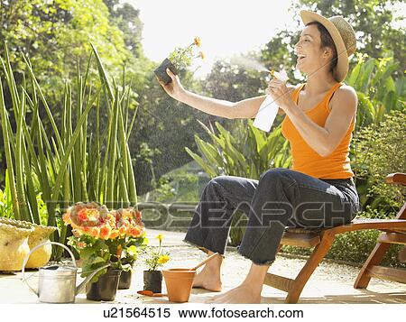 Young woman spraying water on flowers View Large Photo Image Stock Photography - Young woman spraying water on flowers. Fotosearch