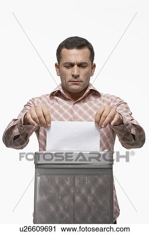 Stock Image - Man feeding paper to paper shredder. Fotosearch