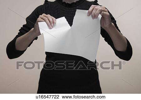 Stock Image - Woman tearing piece of paper (close-up, midsection). Fotosearch