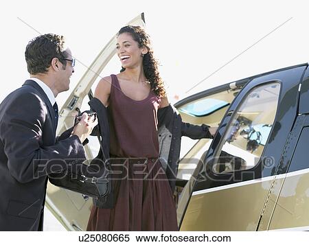 Stock Photography - Businessman helping woman to disembark helicopter. Fotosearch
