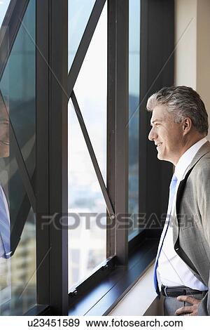 Stock Photo - Businessman looking through window. Fotosearch