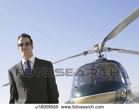 Stock Photography - Businessman standing near helicopter (portrait). Fotosearch