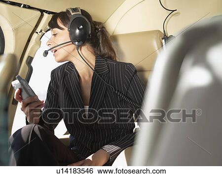 Stock Photograph - Businesswoman using headset in helicopter. Fotosearch