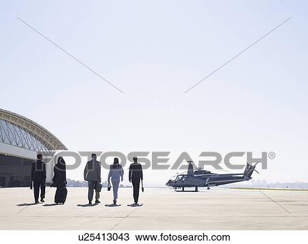 Stock Image - Five businesspeople walking to helicopter. Fotosearch