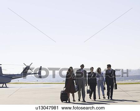 Group of businesspeople walking on runway near helicopter View Large Photo Image Stock Image - Group of businesspeople walking on runway near helicopter. Fotosearch
