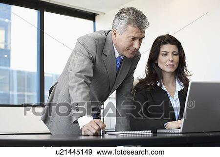 Stock Photo - Two businesspeople working on laptop. Fotosearch