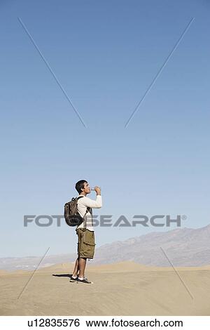 Male hiker drinking water near mountains View Large Photo Image Stock Photograph - Male hiker drinking water near mountains. Fotosearch