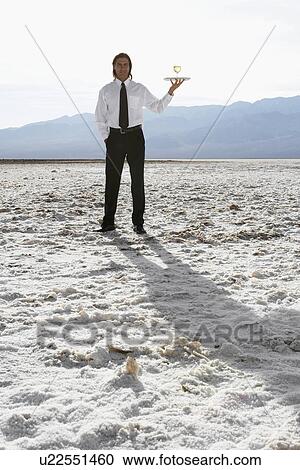 Waiter with wine glass in desert (low angle view) View Large Photo Image Stock Image - Waiter with wine glass in desert (low angle view). Fotosearch