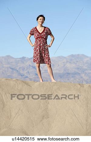 Woman in red dress standing on sand View Large Photo Image Stock Photography - Woman in red dress standing on sand. Fotosearch
