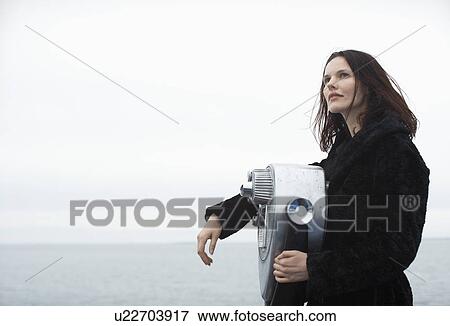 Stock Photo - Young woman leaning on coin-operated binoculars. Fotosearch