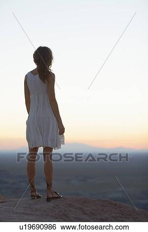 Stock Photograph - Young woman looking at view at sunset. Fotosearch