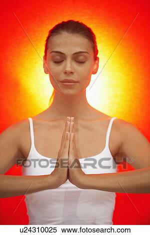 Stock Photography - Woman meditating, yellow light in background. Fotosearch