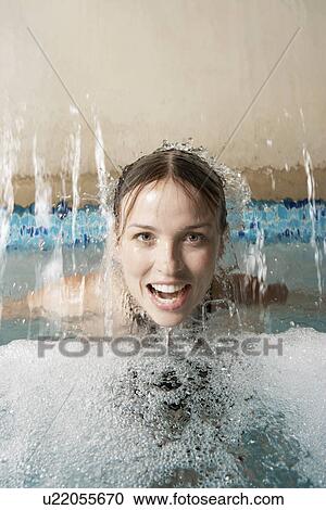 Stock Image - Young woman under waterfall in spa. Fotosearch