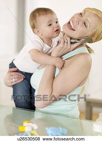 Stock Photo - Mother Holding Son and Talking on Phone. Fotosearch