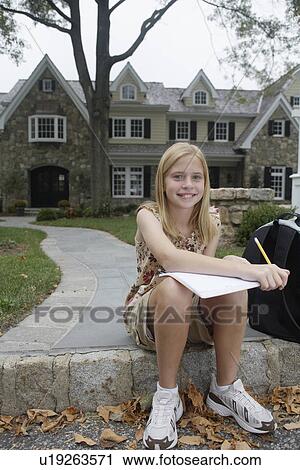 Stock Image - Girl (10-11) doing homework near house, Chatham, New Jersey, USA. Fotosearch