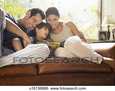 Stock Photography - Parents and son reading book on sofa. Fotosearch