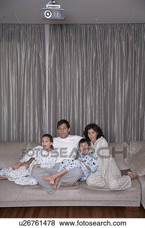 Parents with two children watching TV View Large Photo Image Stock Photo - Parents with two children watching TV. Fotosearch