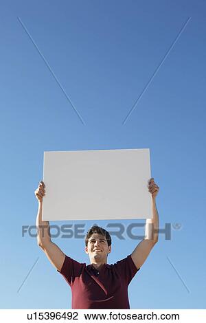 Stock Image - Young man holding blank piece of paper. Fotosearch