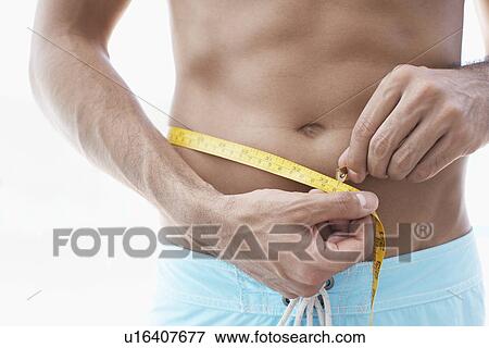 Stock Photo - Young man measuring waist (midsection). Fotosearch