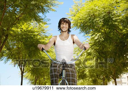 Young man cycling (low angle view) View Large Photo Image Stock Image - Young man cycling (low angle view). Fotosearch