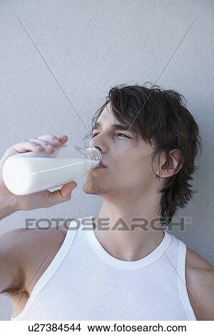 Picture - Young man drinking milk from milk bottle. Fotosearch