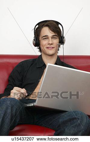 Stock Photo - Young Man Listening to Music Through Laptop. Fotosearch