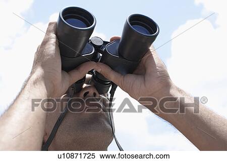 Stock Photography - Young man looking through binoculars. Fotosearch