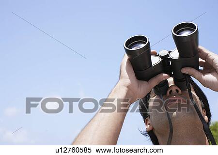 Stock Photography - Young man looking through binoculars. Fotosearch