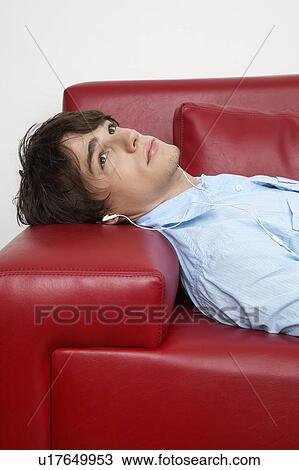 Stock Image - Young Man Lying on Sofa and Looking Up. Fotosearch