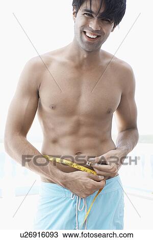 Young man measuring waist View Large Photo Image Stock Image - Young man measuring waist. Fotosearch