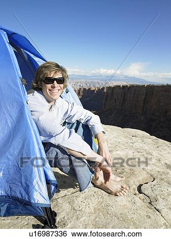Young man sitting in tent, portrait, Moab, Utah, USA View Large Photo Image Stock Photograph - Young man sitting in tent, portrait, Moab, Utah, USA. Fotosearch